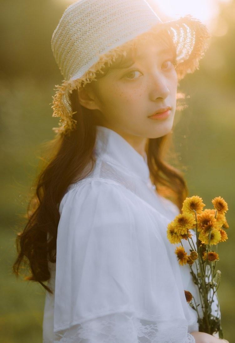 文藝美女潔白長裙?jié)饷芫戆l(fā)手捧鮮花叢林寫真圖片