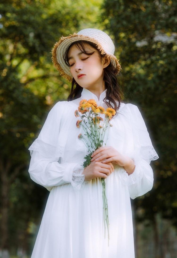 文藝美女潔白長裙?jié)饷芫戆l(fā)手捧鮮花叢林寫真圖片