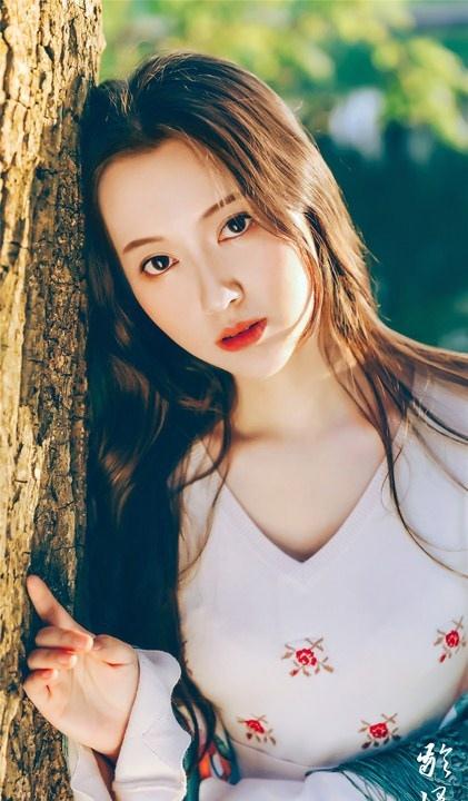 大樹下清純靈動美女手捧蘋果纖細(xì)身形圖片