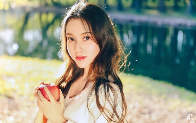 大樹下清純靈動美女手捧蘋果纖細(xì)身形圖片