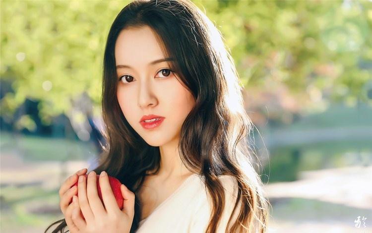 大樹下清純靈動美女手捧蘋果纖細(xì)身形圖片