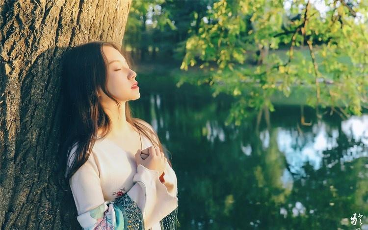 大樹下清純靈動美女手捧蘋果纖細(xì)身形圖片