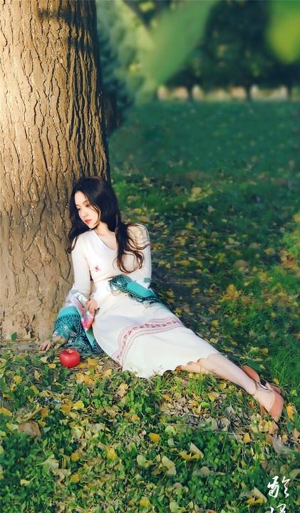 大樹下清純靈動美女手捧蘋果纖細(xì)身形圖片